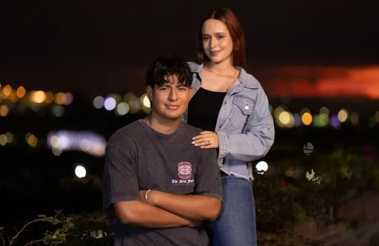 Omar y Tati de noche, con la ciudad iluminada detrás